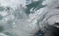 An NOAA satellite image shows the northeastern portion of the United States with swirls of black, blue-green gray and white at varying saturation. Thin border lines are indicated in black. 