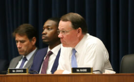 Photo shows three Congresspeople seated at a House hearing, with placards for Graves and Massie visible