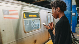 A woman looks at her smartphone while waiting for a New York City subway train