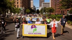  Acting US Secretary of Labor Julie Su marches with attendees during a parade in front of a banner that reads Tradeswomen Build Nations