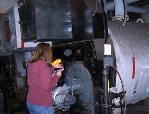 Community Environmental Center technician checks a boiler during an energy audit of a multifamily building.